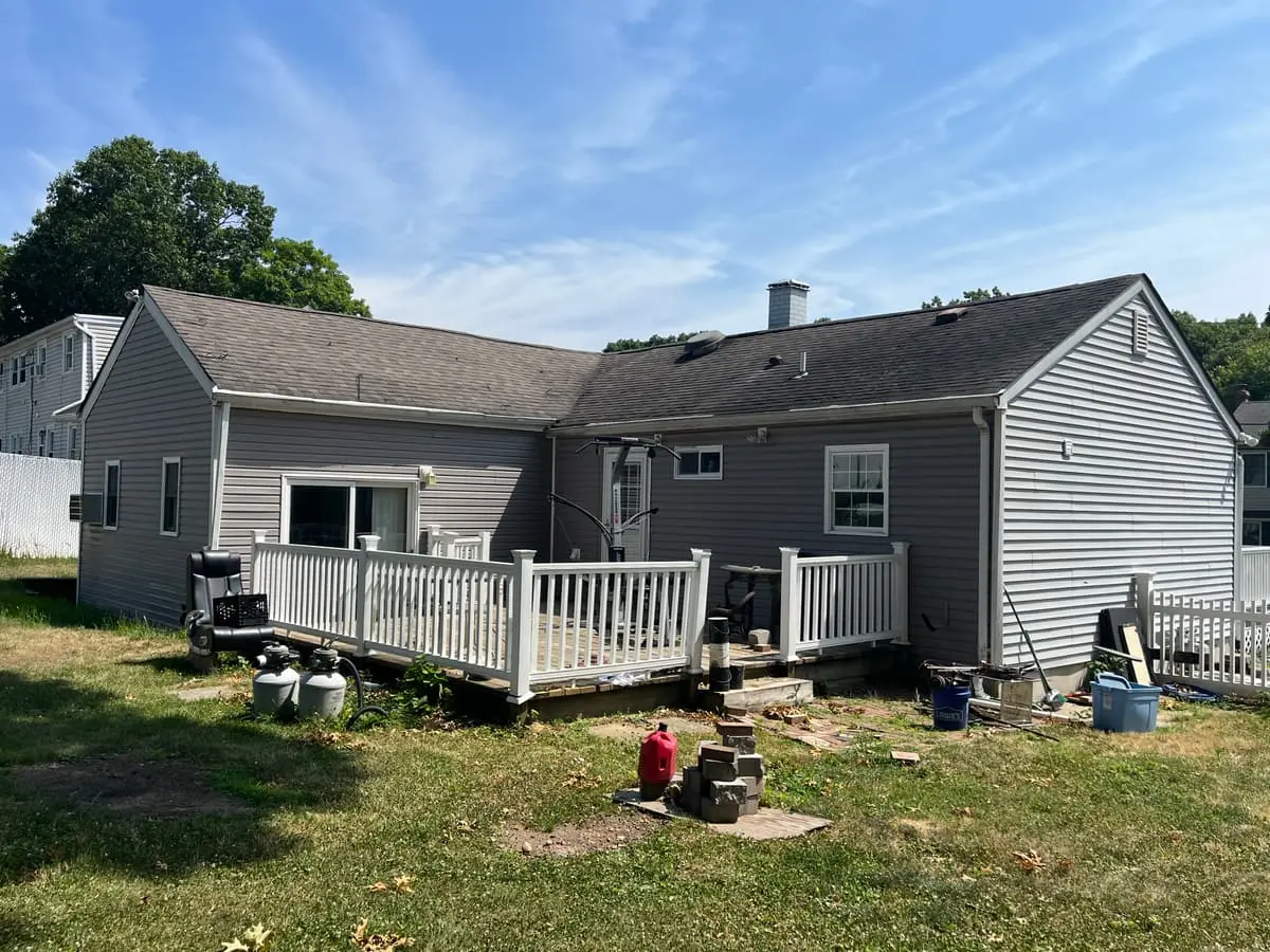 Back of a gray ranch with a deck and a deep yard, Ronkonkoma, NY