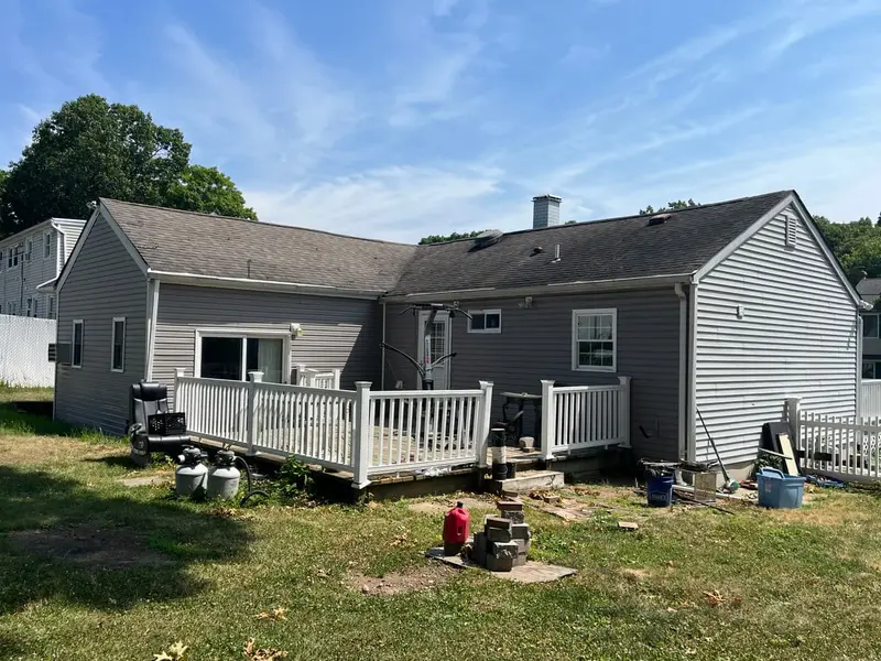 Back of a gray ranch with a deck and a deep yard, Ronkonkoma, NY