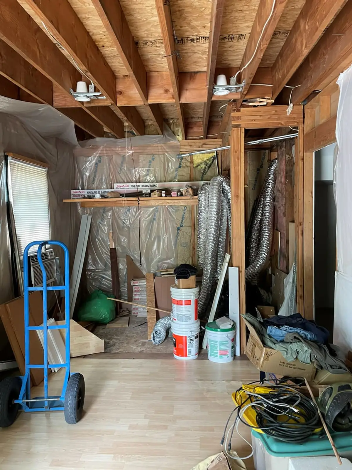 Selling a house for a job relocation in Ronkonkoma: half-framed room with open ceiling joists and stored equipment