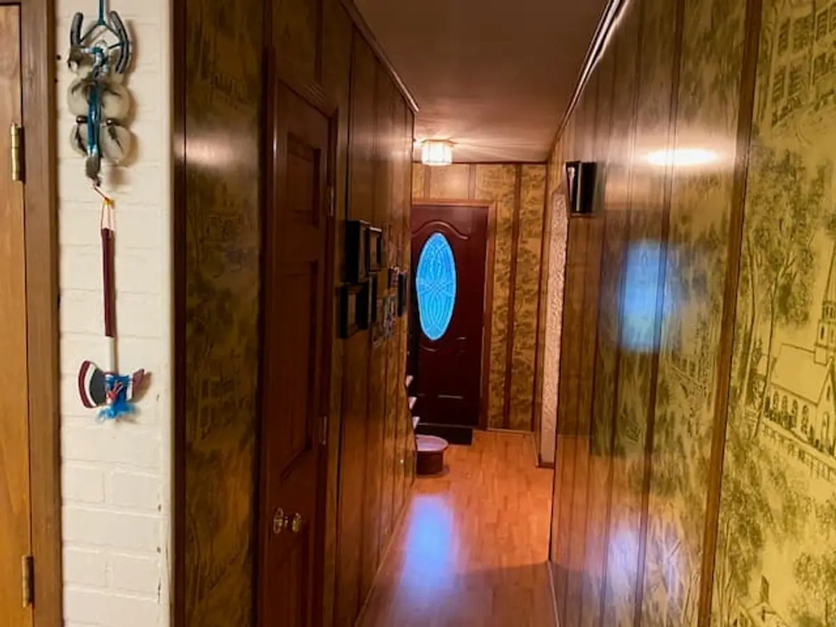 Selling an inherited house in Ronkonkoma: hallway lined with old patterned wallpaper and wood paneling