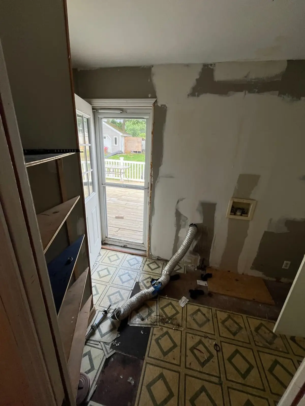 Selling estate property as an executor in Ronkonkoma: laundry room with torn vinyl flooring and an open wall