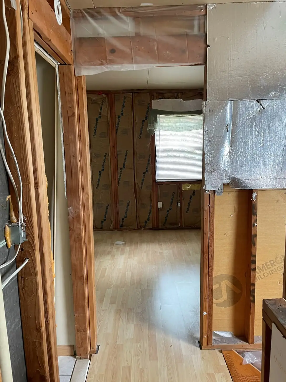 Selling a fire-damaged house in Ronkonkoma: room with the walls opened to the insulation and plastic sheeting