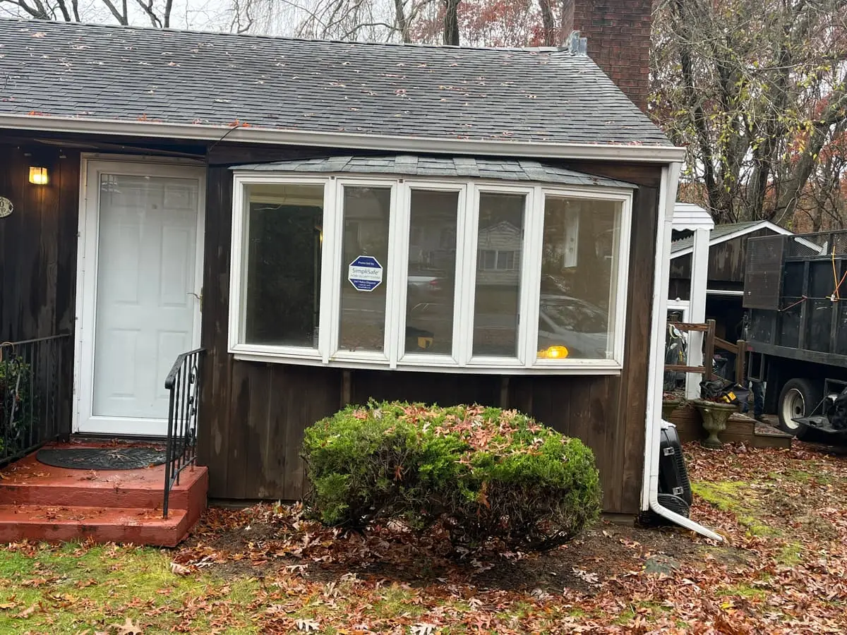 Selling a house in pre-foreclosure in Ronkonkoma: small dark-shingled cottage with a bay window and a brick stoop