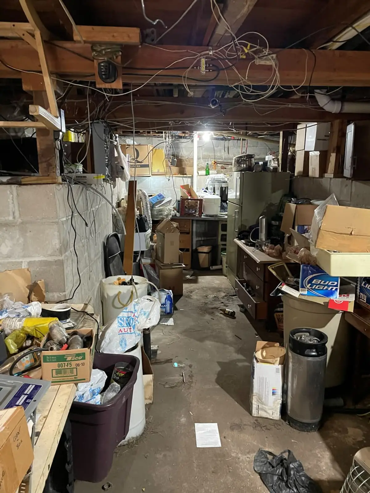 Selling a house in bankruptcy in Ronkonkoma: unfinished basement crowded with boxes under exposed joists