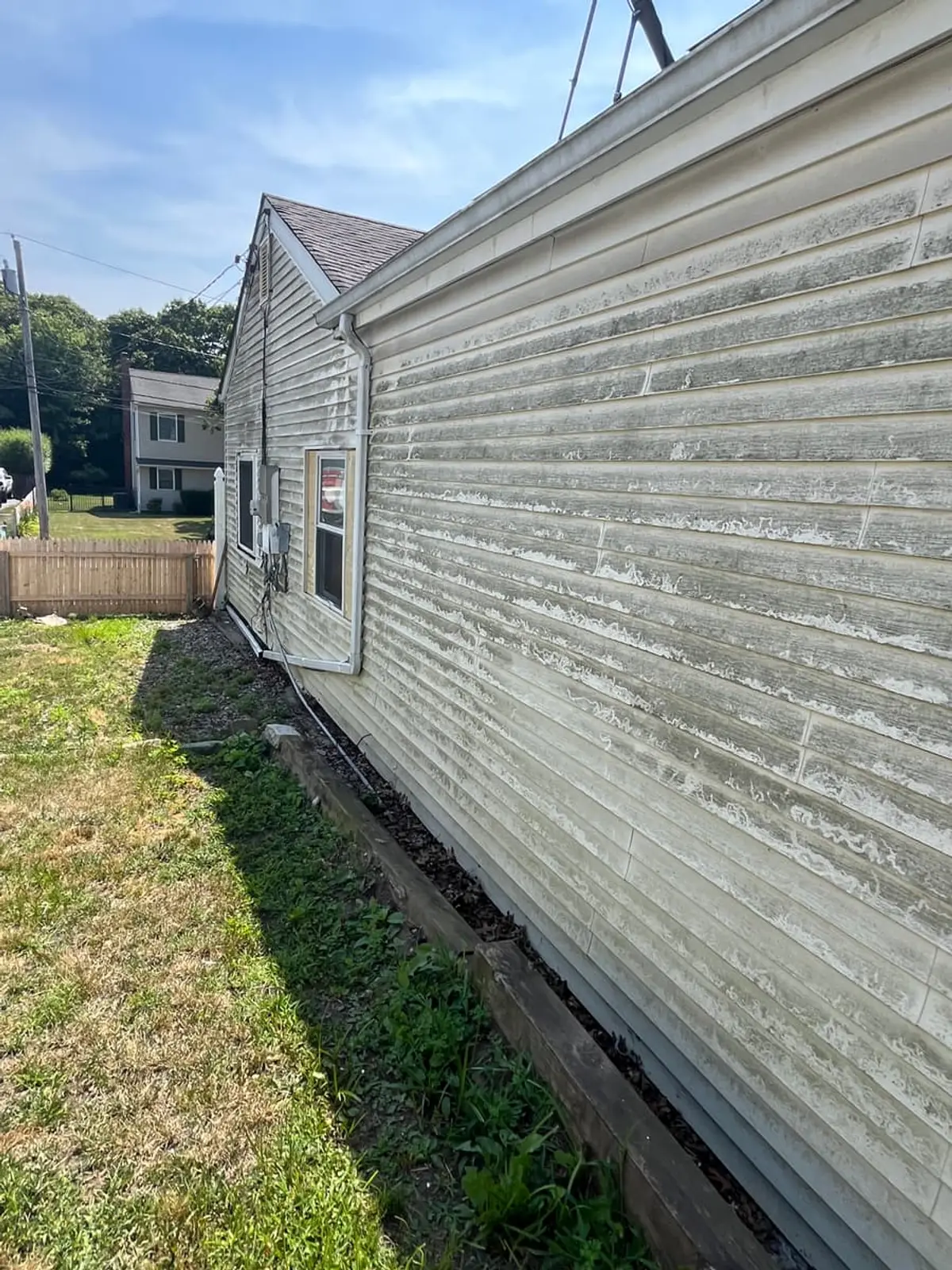 Selling a house as-is in Ronkonkoma: weathered, mildewed siding along the side of a ranch